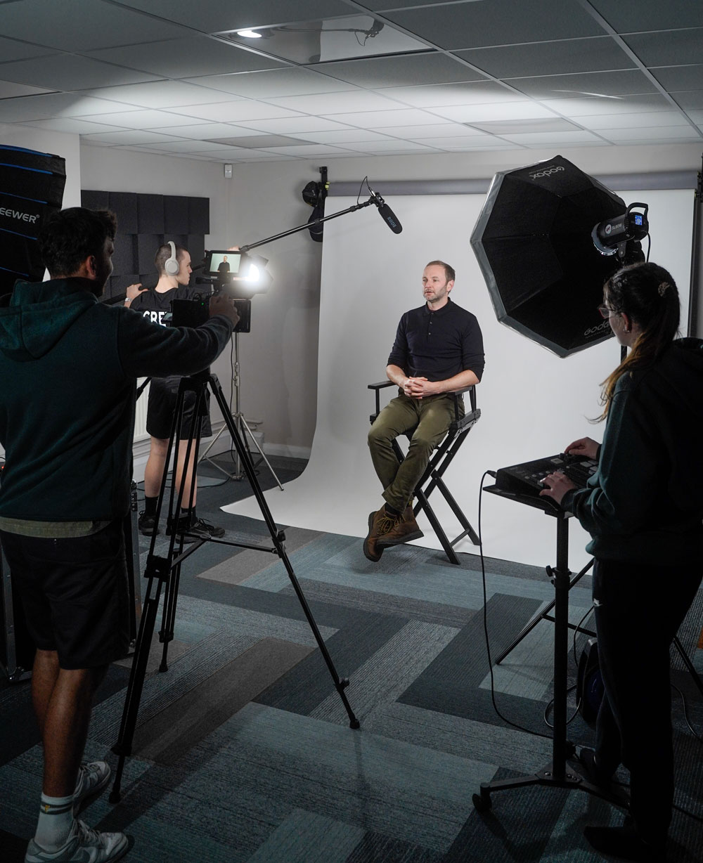 A group of people in a video production company studio with a camera and a tripod, with lighting and audio equipment, ready to capture a moment.