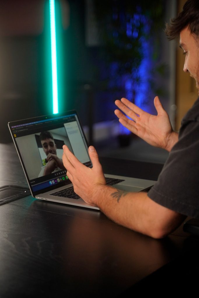 Image of a man with hands up at a desk, on a video call with a client part of a video production company in chorley.